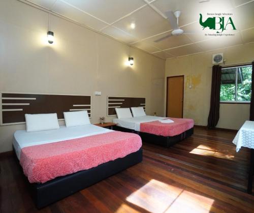 京那巴当岸Borneo Jungle Adventure的铺有木地板的客房内的两张床