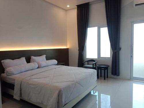 TjolomaduGenio Syariah Hotel Solo的卧室设有一张白色大床和一扇窗户。