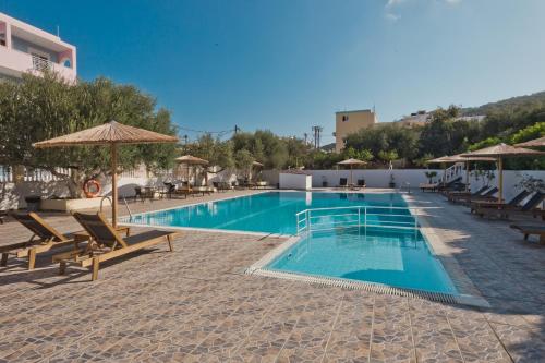 卡尔帕索斯里贾纳公寓式酒店的度假村内带椅子和遮阳伞的游泳池