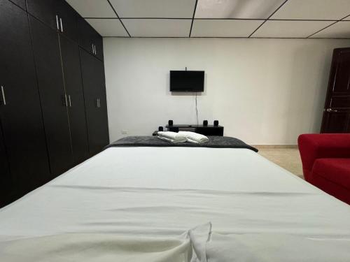 佩雷拉Acogedor apartaestudio ubicado en la zona rosa de Pereira的卧室配有一张白色大床和红色椅子