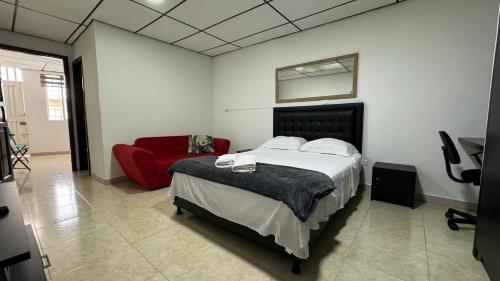 佩雷拉Acogedor apartaestudio ubicado en la zona rosa de Pereira的一间卧室配有一张床和一张红色的沙发