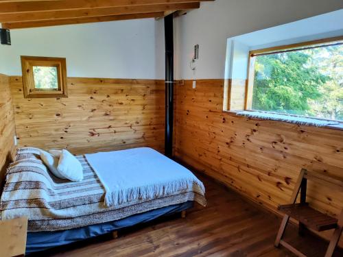 圣卡洛斯-德巴里洛切Cabaña de montaña Ruca Calel的木制客房的一间卧室配有一张床,设有窗户