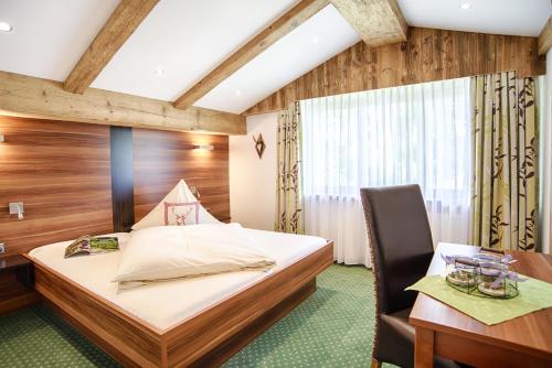 米斯巴赫温德尔施泰因潘森酒店的一间卧室配有一张床、一张桌子和一把椅子
