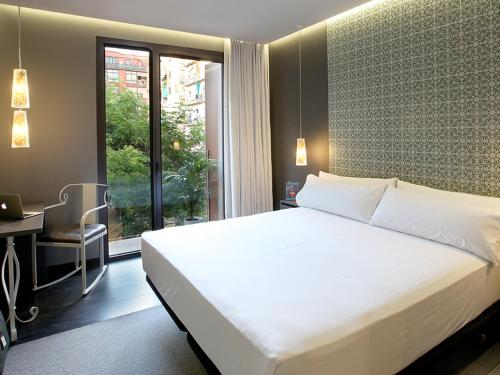 巴塞罗那Axel TWO Barcelona 4 Sup - Adults Only的一间卧室配有一张床、一张书桌和一个窗户。