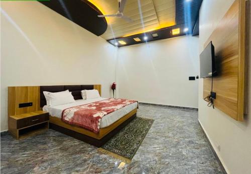 乌贾因Lotus Palm Retreat - Full Villa (By A.P. Villa's)的一间卧室配有一张床和一台平面电视