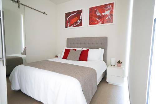 阿德莱德Walkerville Bliss的白色卧室配有一张带红色枕头的大床