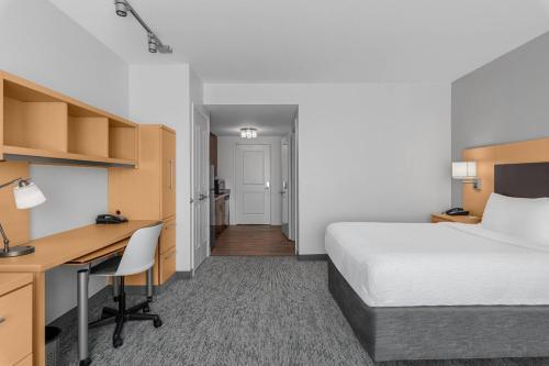 奥罗拉盖特韦帕克丹佛机场陶纳普雷斯套房酒店的酒店客房带一张床铺、一张书桌和一间卧室