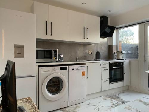 CarshaltonApartment C, a one bedroom Flat in south London的厨房配有洗衣机和微波炉。