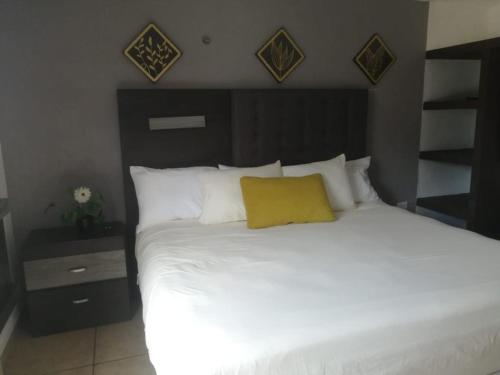 坎昆La Luna的卧室配有白色床和黄色枕头