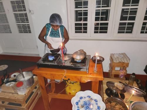科伦坡CEYLON STAYZ的一位在厨房里用点燃的蜡烛准备食物的女人