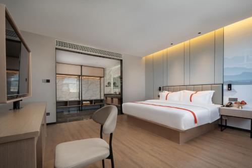 腾冲格林东方酒店(腾冲东湖公园店)的一间卧室配有一张床、一张书桌和一台电视