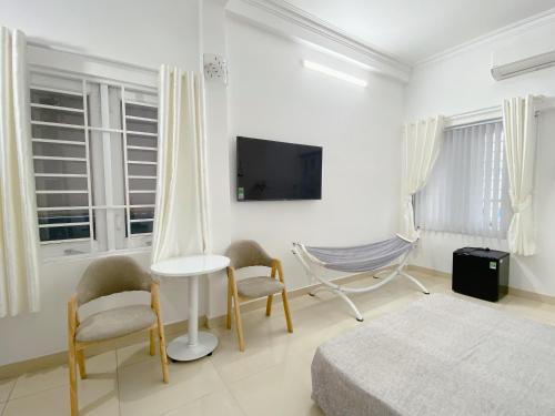 胡志明市SAIGONESE Studio的白色的客房配有床、椅子和电视