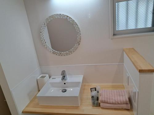 那霸Ｃｌｅａｎ　Ｈｏｔｅｌｓ　ｉｎ　Ｎａｈａ　Ｉｚｕｍｉｚａｋｉ的浴室设有白色水槽和镜子