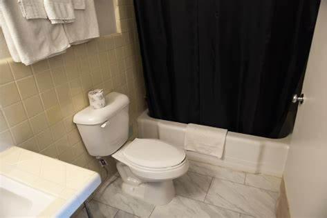 DermottAmerican Inn的浴室设有卫生间和黑色淋浴帘