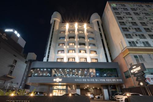 大田Workers Hotel Daejeon by Aank的一座有照明的建筑,前面有汽车停放