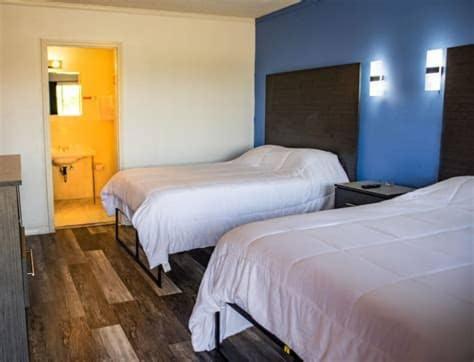 DermottAmerican Inn的酒店客房设有两张床和蓝色的墙壁。