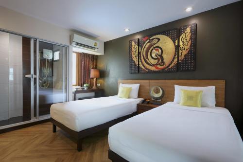 曼谷维新安睡酒店的一间卧室设有两张床和淋浴。