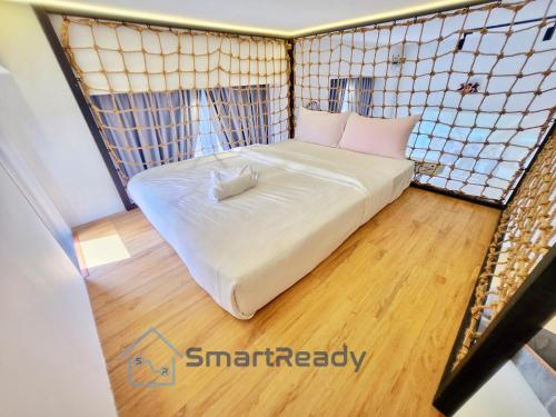 Kampong PendasSunway GRID by SR Home的小房间设有白色的床和木地板