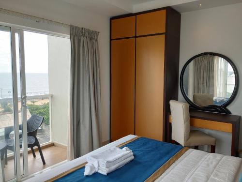 尼甘布OCEAN BREEZE - WAVES LUXURY CONDO的一间带床和镜子的卧室以及一个阳台