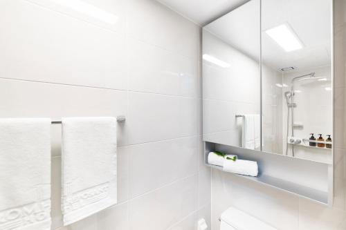 釜山From H Reposant Hotel Busnan Seomyeon的白色的浴室设有镜子和白色毛巾