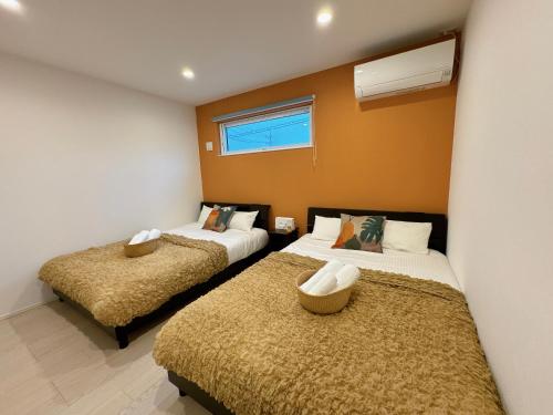 恩纳グランディオーソ沖縄プールヴィラ恩納７的橙色墙壁客房的两张床