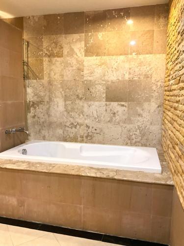 攀瓦海滩Bel Air Cape Panwa Resort Phuket的带浴缸的浴室和石墙