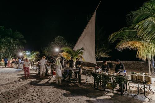 普瓦尼梅查恩加尼LUX Marijani Zanzibar的一群人晚上在海滩上围着桌子站着