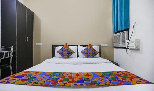 KakarmathaFabHotel Lily Grand的一间卧室配有一张带彩色毯子的床