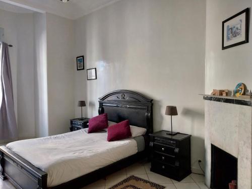 卡萨布兰卡Cosy Art Deco Apart的一间卧室配有一张带红色枕头的床和壁炉