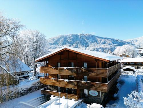 巴特维塞Hotel Villa Lago Garni的雪中小木屋,背景是群山