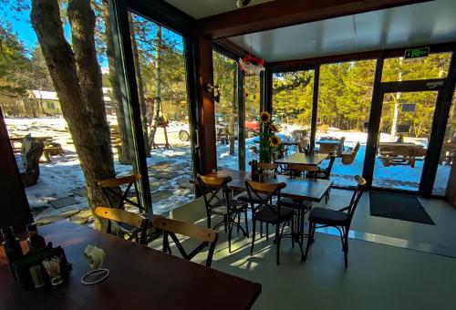 ZheleznitsaPinusVillas Conference Lodge的餐厅设有桌椅和大窗户。