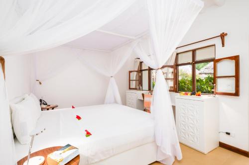 南威Sandies Baobab Beach Zanzibar的白色卧室配有床和桌子