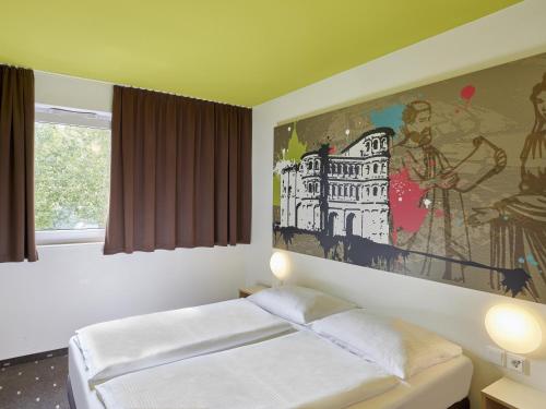 特里尔特里尔住宿加早餐酒店的卧室配有一张床,墙上挂有绘画作品