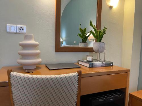 海若克利欧格列柯酒店 的一张带镜子的桌子、一台笔记本电脑和花瓶