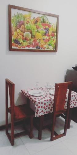 康提Chef Naturelle's Guest House的一张桌子、两把椅子和墙上的一幅画