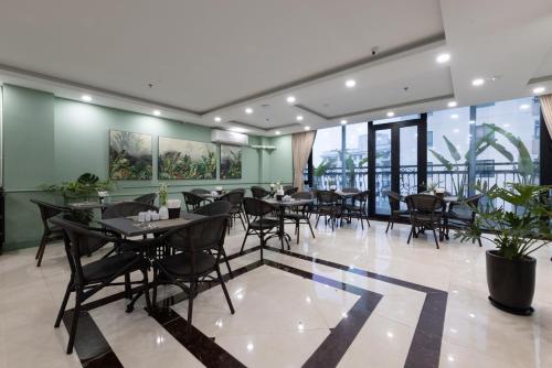 河内Nature Hotel的餐厅设有桌椅和大窗户。