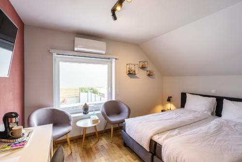 奥斯坦德Villa Cecha B&b &Wellness的一间卧室配有一张床、两把椅子和一个窗户