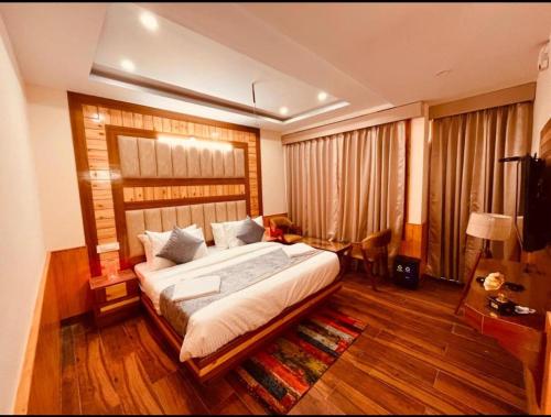 大吉岭Hotel Lee Green- best family hotel in Darjeeling的铺有木地板的客房设有一间带大床的卧室