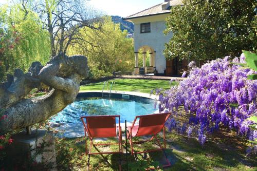 基亚瓦里Relais Rantegosa - Holiday home的两把椅子和一个游泳池,位于一个种有紫色花卉的庭院内