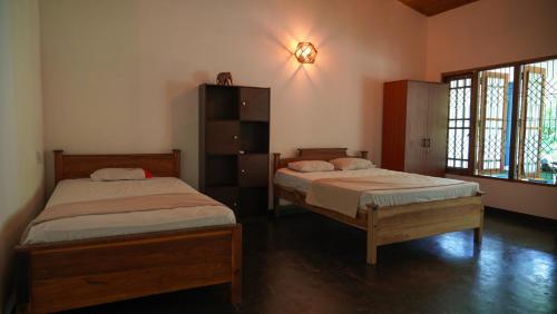 锡吉里亚Jayanti's的一间卧室设有两张床和窗户。