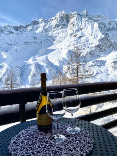 布勒伊-切尔维尼亚Ski paradise - Cielo alto Cervinia的桌子上放有一瓶葡萄酒和两杯酒