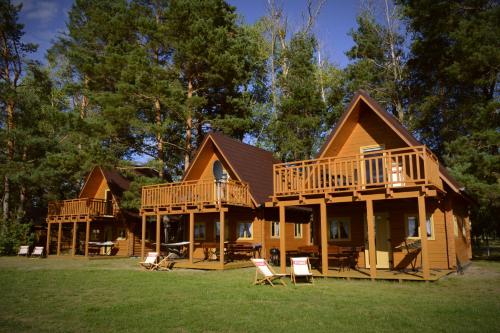 什切齐内克Camping Szczecinek Domy Wypoczynkowe的大型小木屋设有2个甲板和椅子