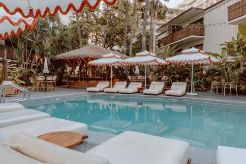 檀香山White Sands Hotel的一个带躺椅和遮阳伞的游泳池