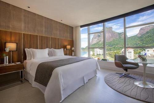 里约热内卢Hotel nacional的一间卧室配有一张大床、一张桌子和一把椅子