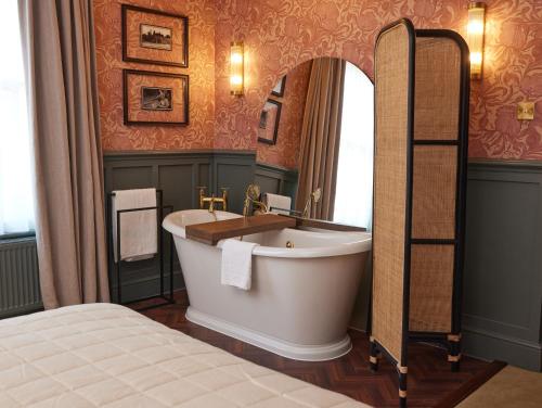贝里圣埃德蒙兹Dog and Partridge by Greene King Inns的一间带大浴缸和镜子的浴室