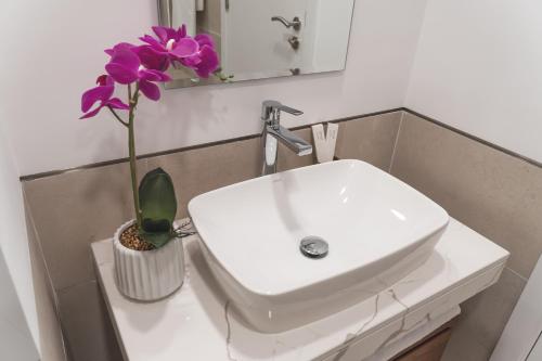 迪拜New 2 bedroom entire apartment in Madinat Jumeirah Living的浴室水槽,花瓶里装紫色的花