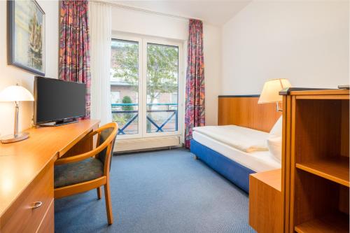 诺德奈Gästehaus Gelsenkirchen的配有一张床、一张书桌和一扇窗户的酒店客房