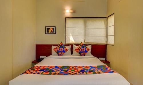 浦那FabHotel Sky Vista Inn的一间卧室配有一张带色彩缤纷枕头的大床