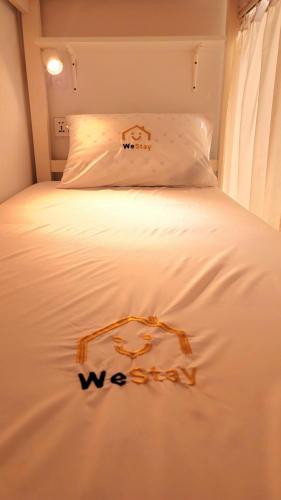 迪拜WeStay Ladies Hostel的一张白色的床,上面有标牌