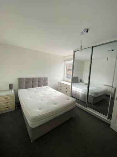 伦敦Remarkable 1-Bed Apartment in Putney Village的一间白色卧室,配有两张床和镜子